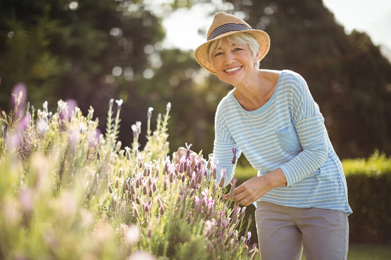 Woman smiling in a garden with flowers.